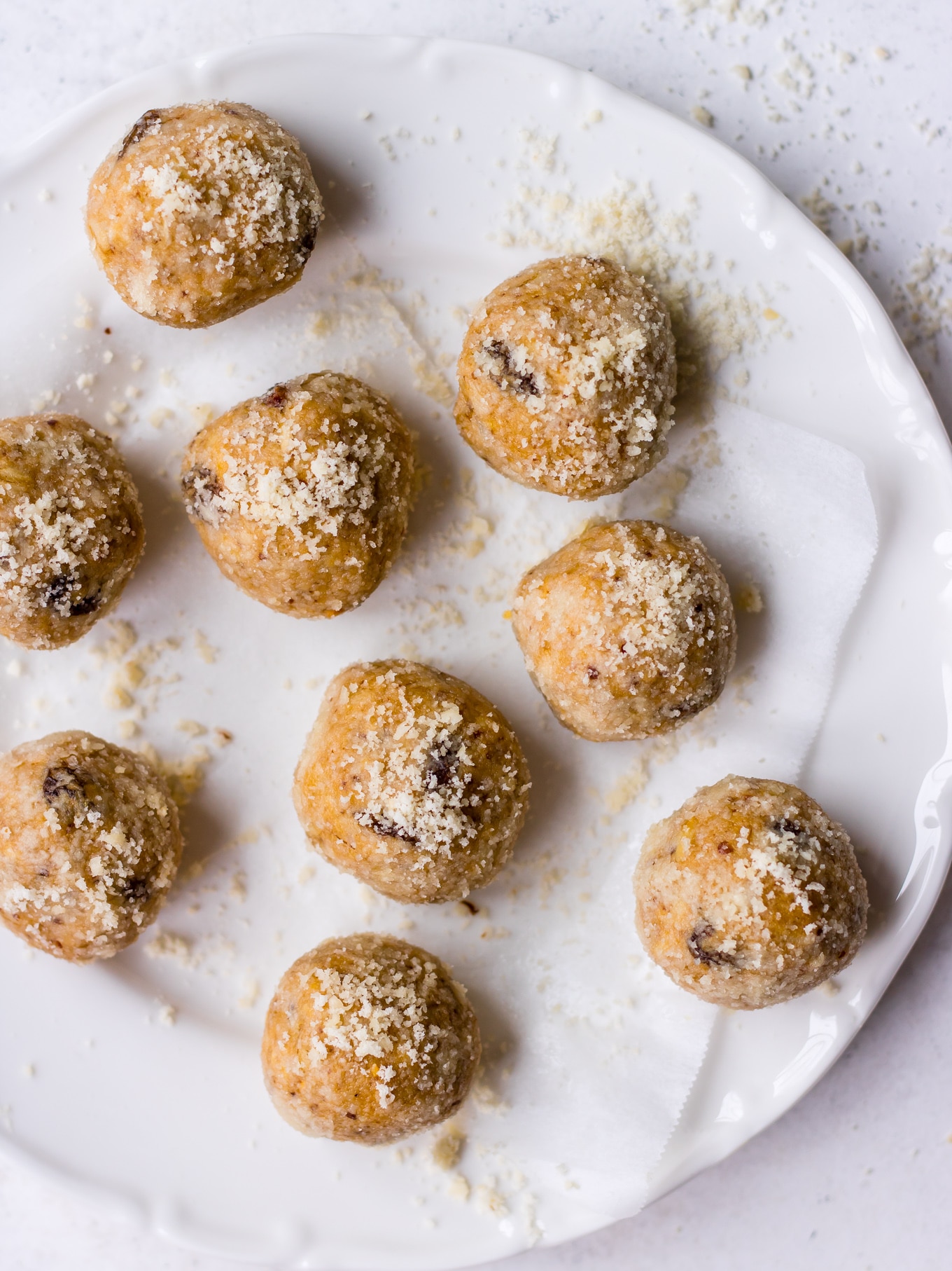 No bake Lactation Bites arranged on a white plate, scattered with almond meal (by Nourish Every Day)