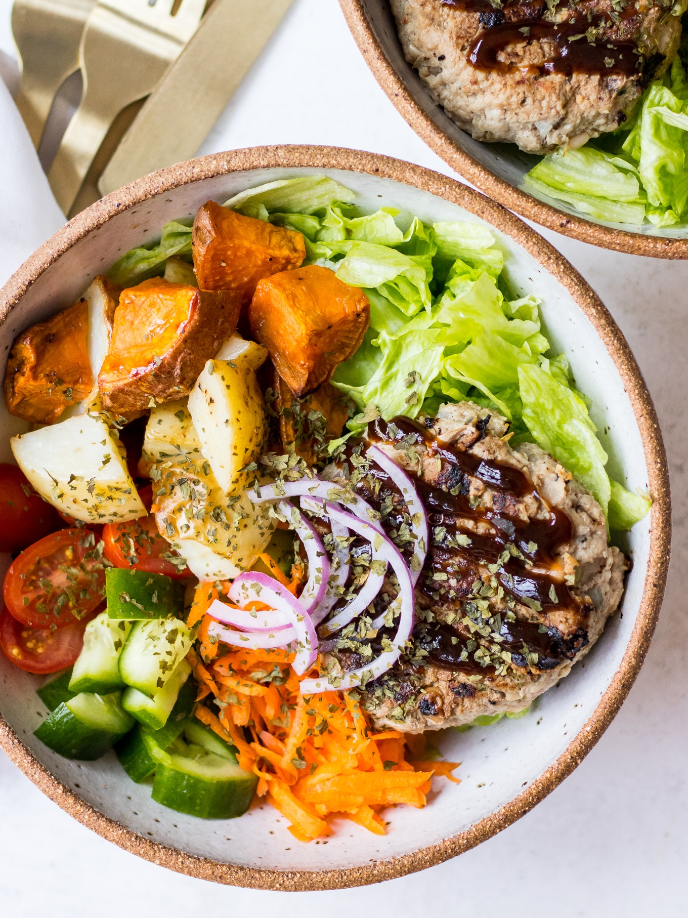 Turkey burger patties in a ceramic bowl with mixed salad and bbq sauce