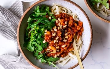 Vegan bolognese sauce topped with pine nuts