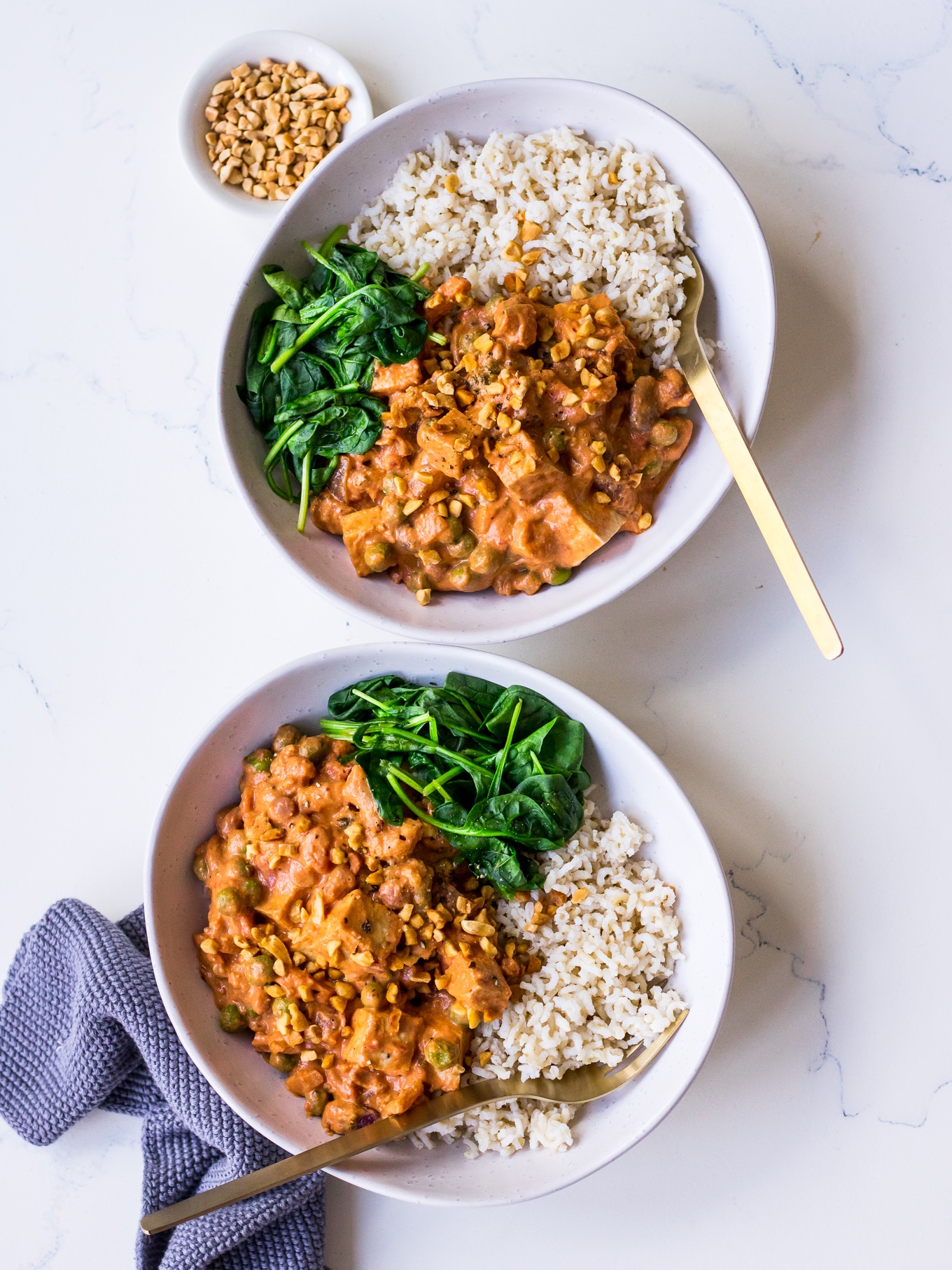 Two bowls with vegetarian curry, brown rice and spinach