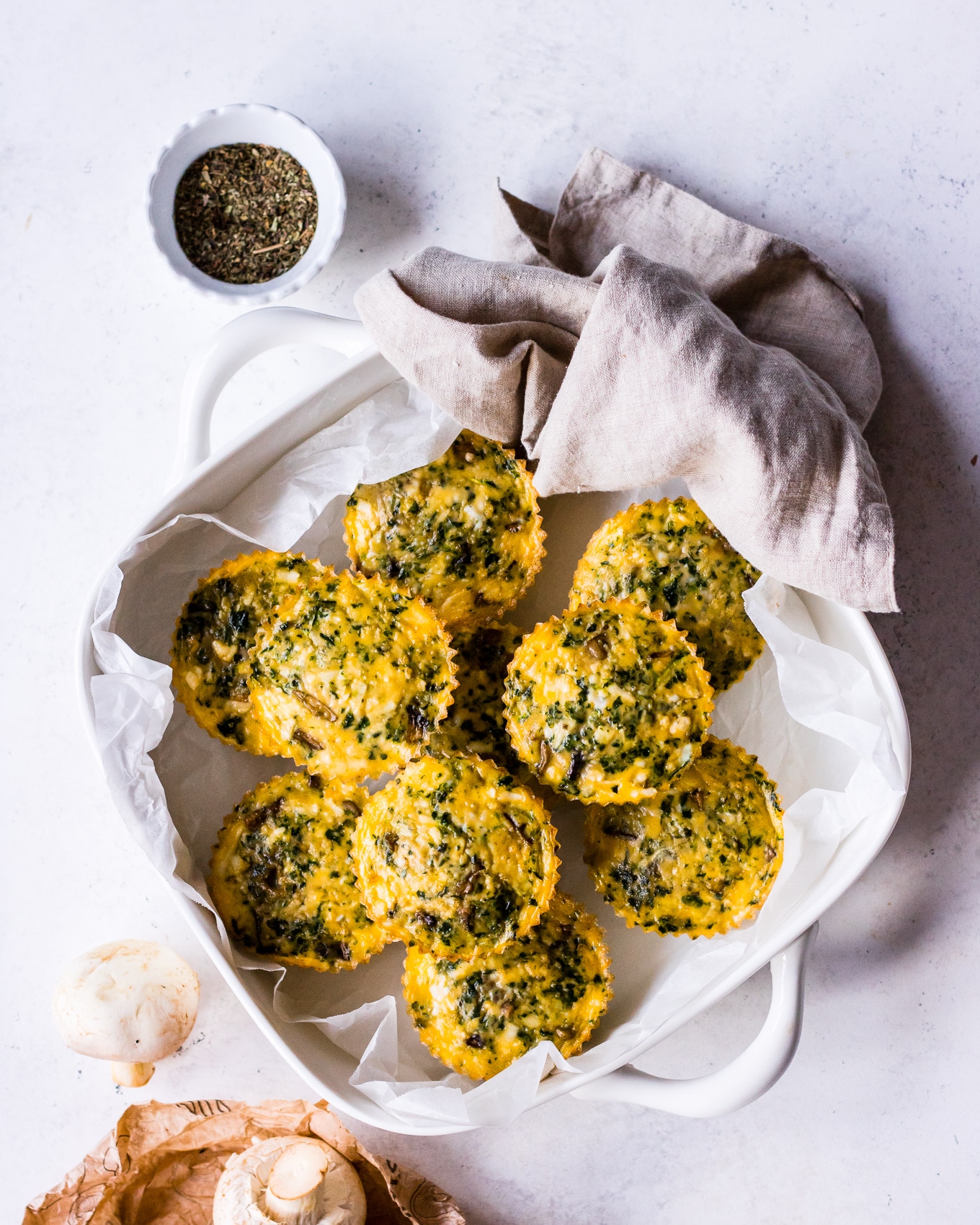 Top view of spinach, mushroom and halloumi egg muffins in white dish