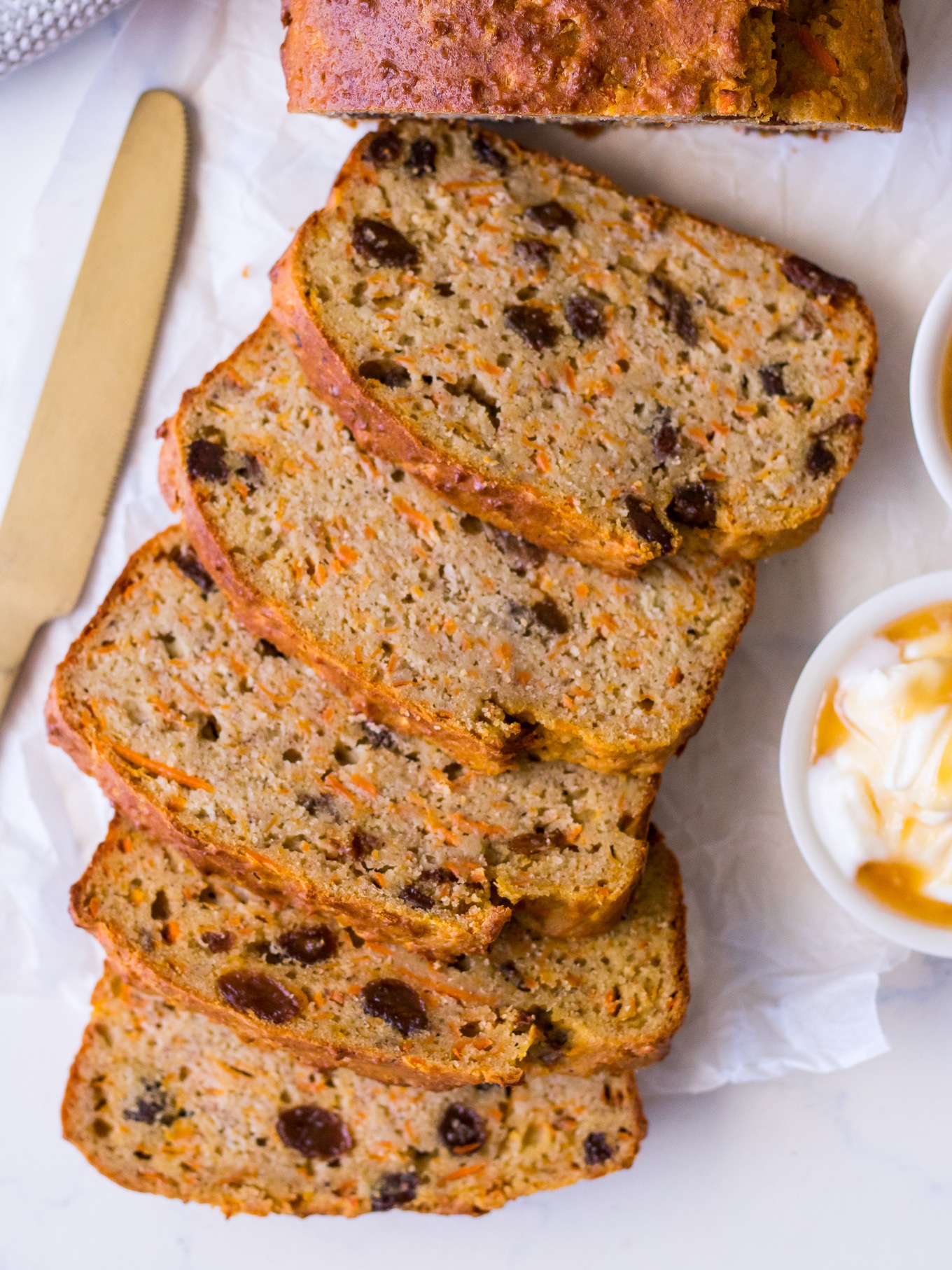 Slices of banana, carrot and sultana loaf cake against a white background