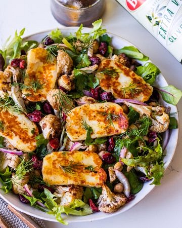Close view of roasted cauliflower salad topped with fried halloumi slices