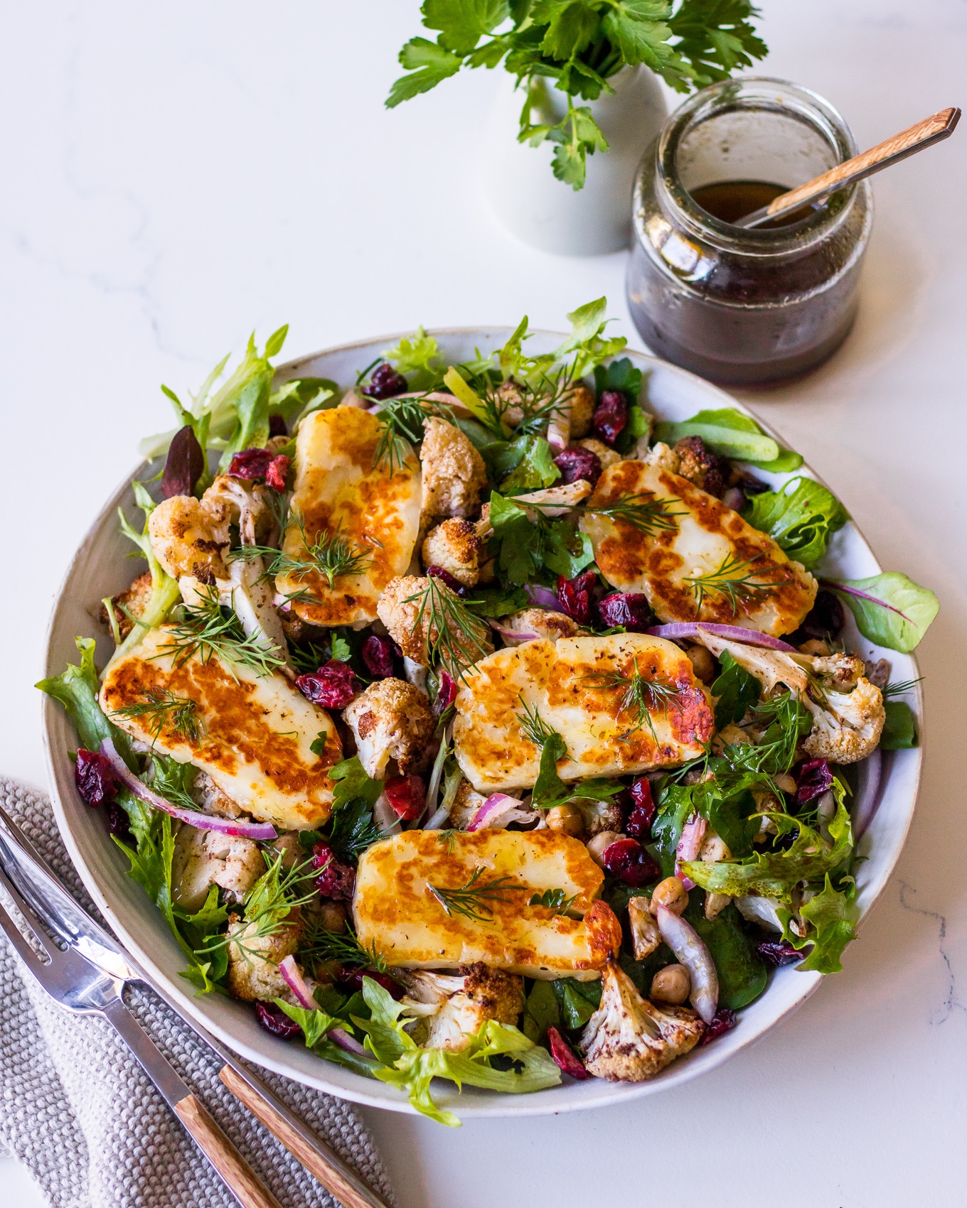 Roasted cauliflower salad topped with pan fried halloumi cheese slices and balsamic dressing in jar