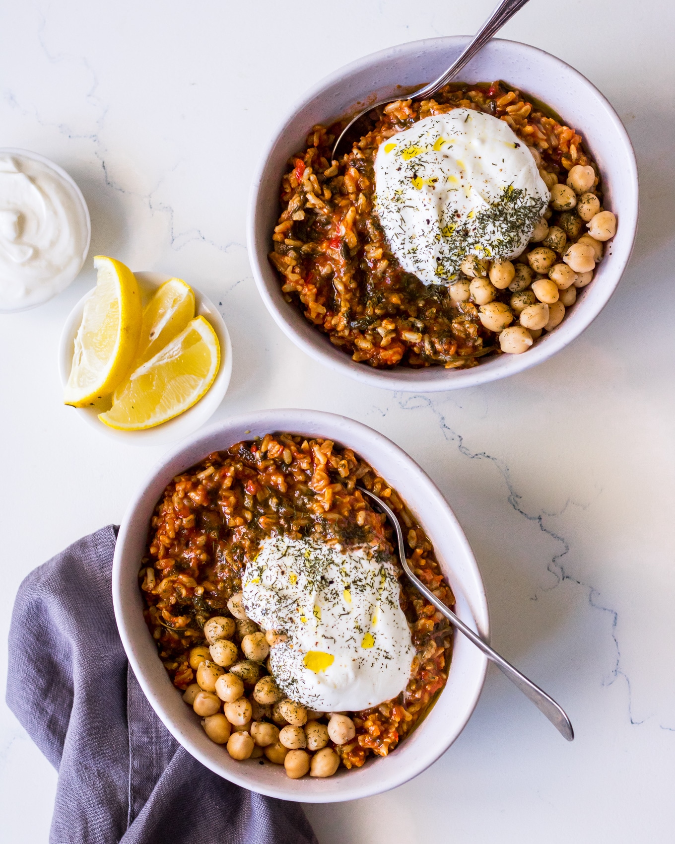 Top view bowls of Greek spanakorizo topped with chickpeas, Greek yoghurt, herbs and lemon