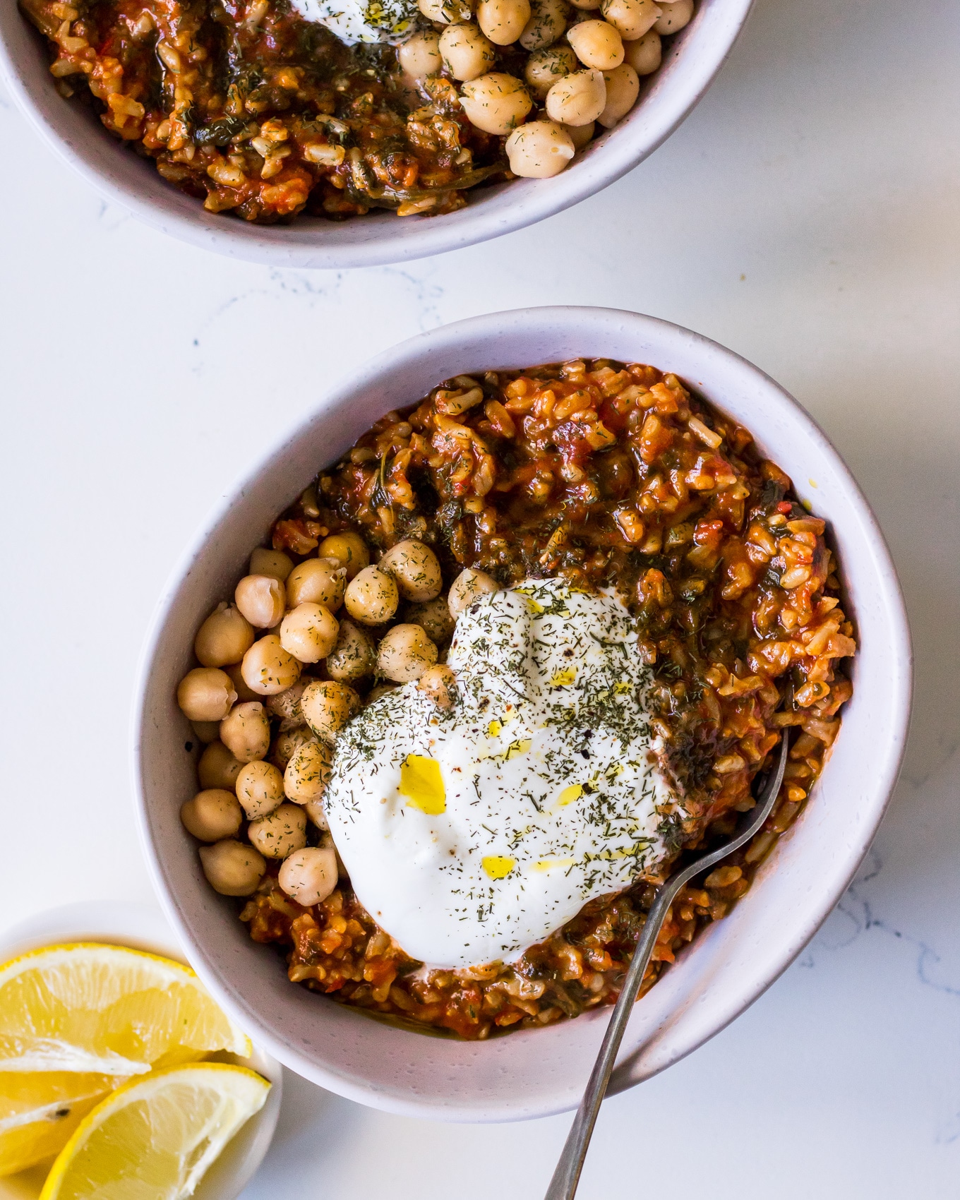 White bowl filled with spanakorizo (Greek spinach and rice), chickpeas and yoghurt with lemon and herbs