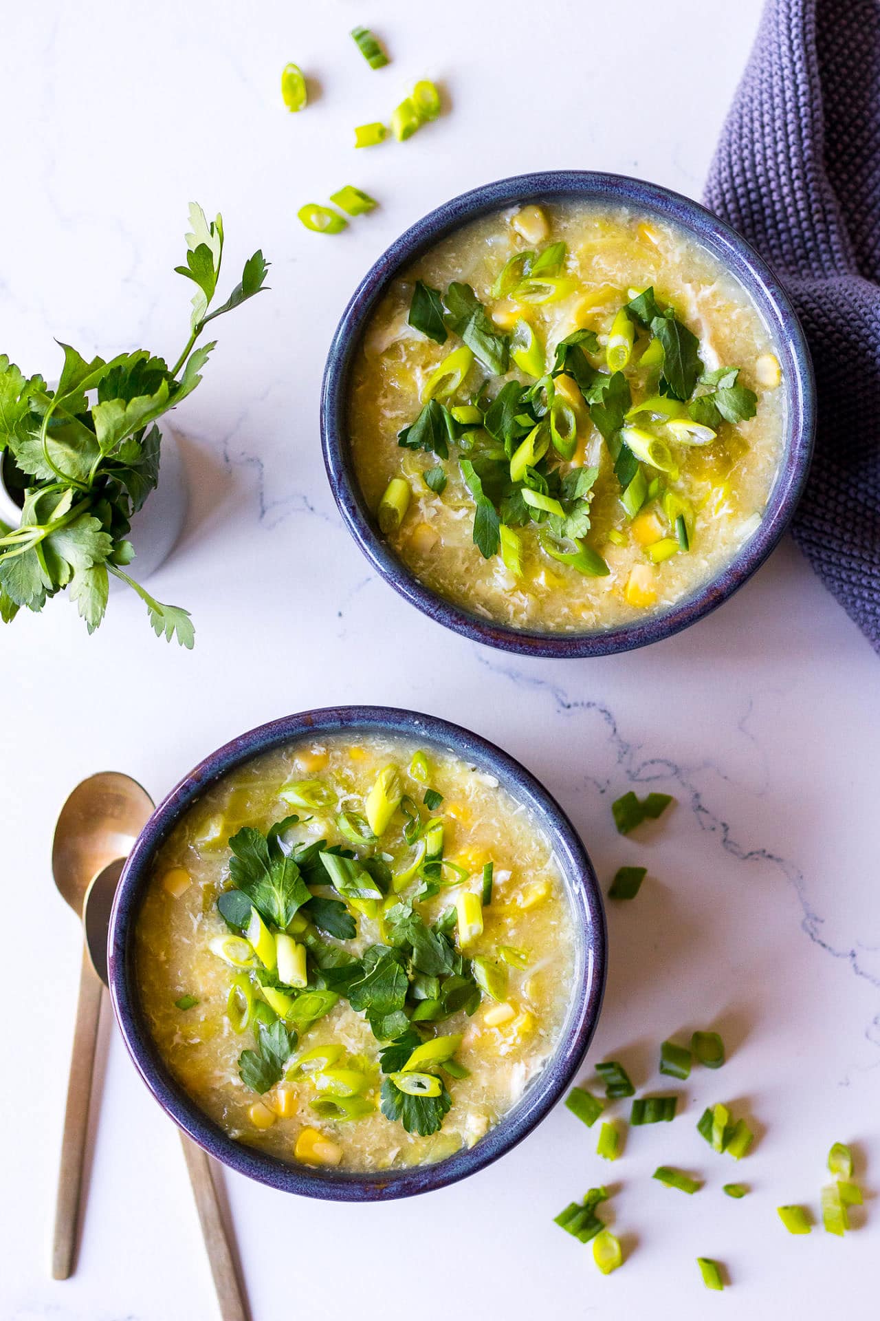 Two ceramic bowls of chicken sweet corn soup with herbs