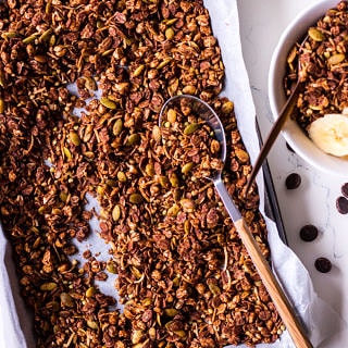 Tray of chocolate olive oil granola with a spoon, small bowl to the side