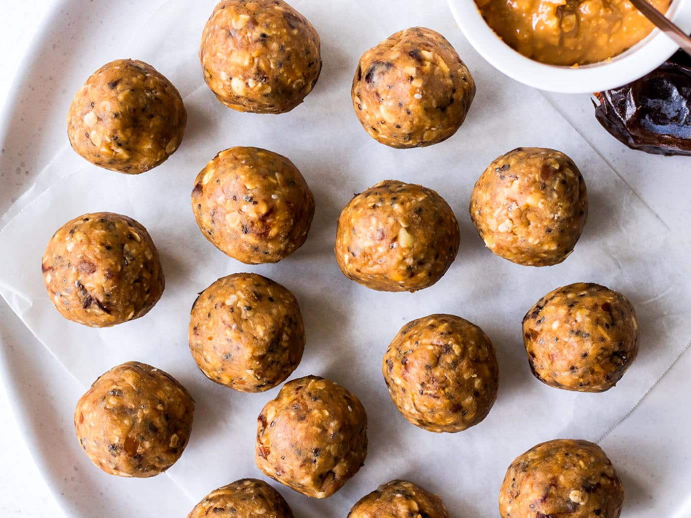 Peanut butter date energy balls arranged on a white ceramic plate