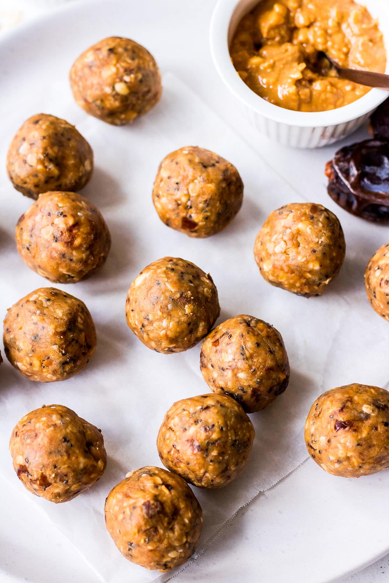 White ceramic plate with peanut butter, date and chia seed energy balls, medjool dates and mini bowl of crunchy peanut butter