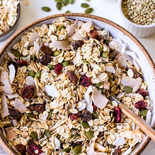 Large ceramic bowl filled with oat muesli with coconut flakes, pumpkin seeds and dried fruit