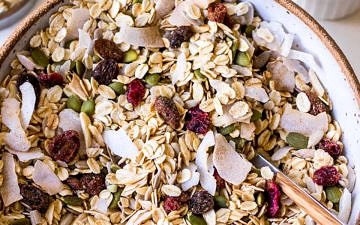 Large ceramic bowl filled with oat muesli with coconut flakes, pumpkin seeds and dried fruit