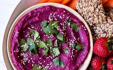Dip platter with beet dip, carrot sticks, cashews, strawberries and seeded crackers