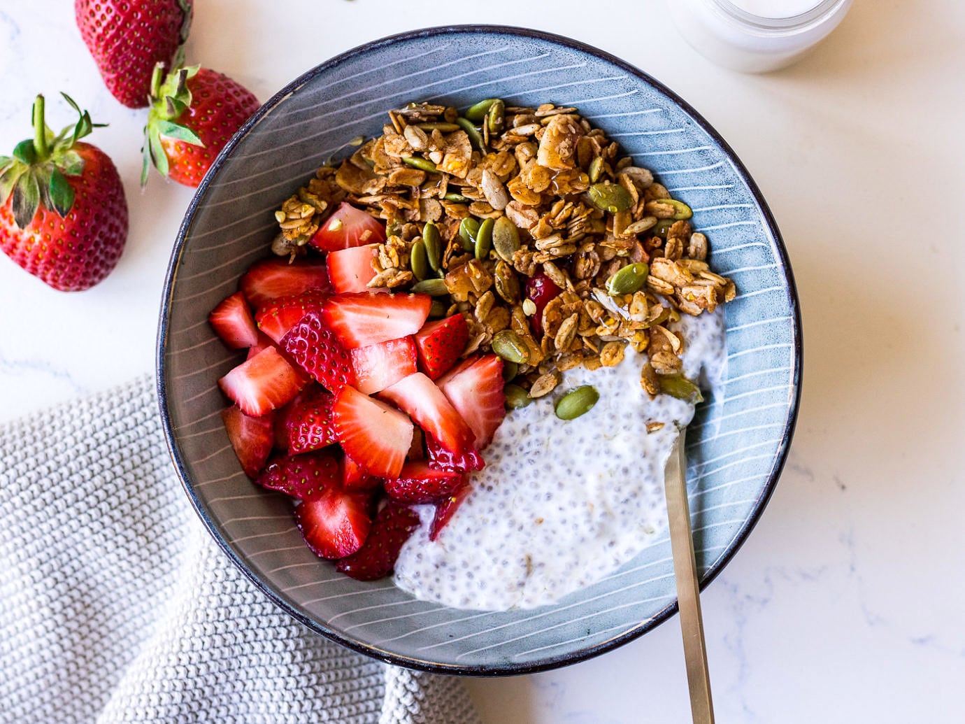 Blue ceramic bowl with granola, strawberries and chia pudding