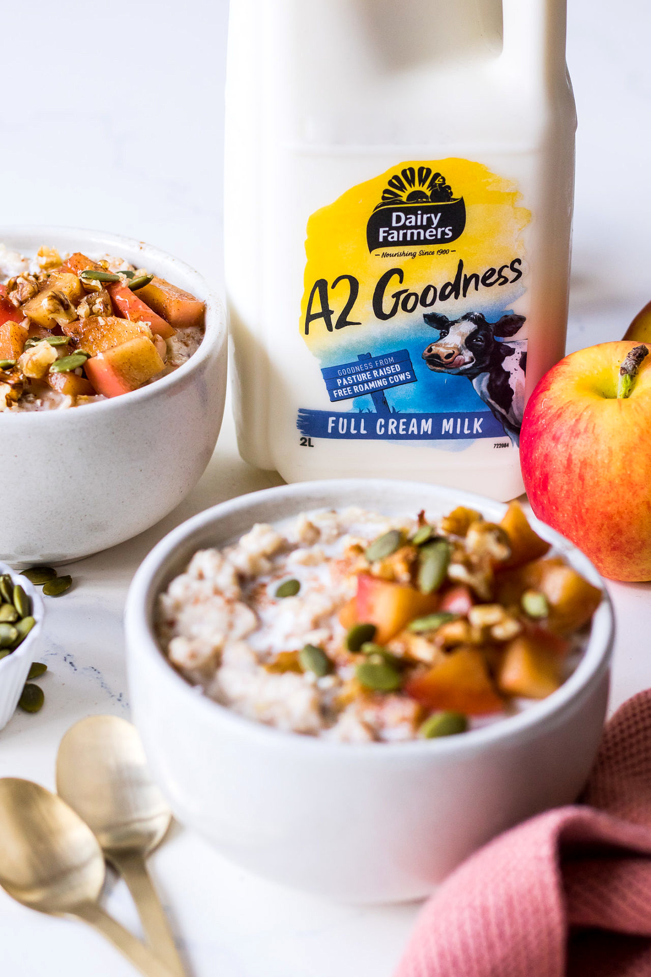 Dairy Farmers A2 Goodness Milk bottle pictured with bowls of apple cinnamon porridge