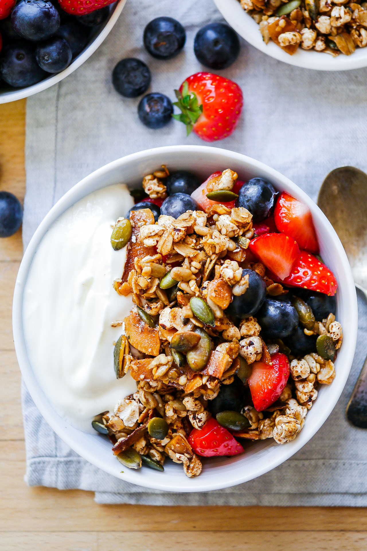 Small light blue ceramic bowl with yoghurt, toasted muesli, strawberries and blueberries