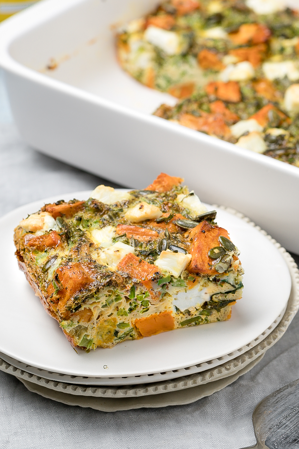 Slice of sweet potato, broccoli and feta frittata on a small white side plate