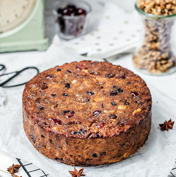 Healthy Christmas fruit cake on top of baking paper and wire rack, ingredients and scales in background