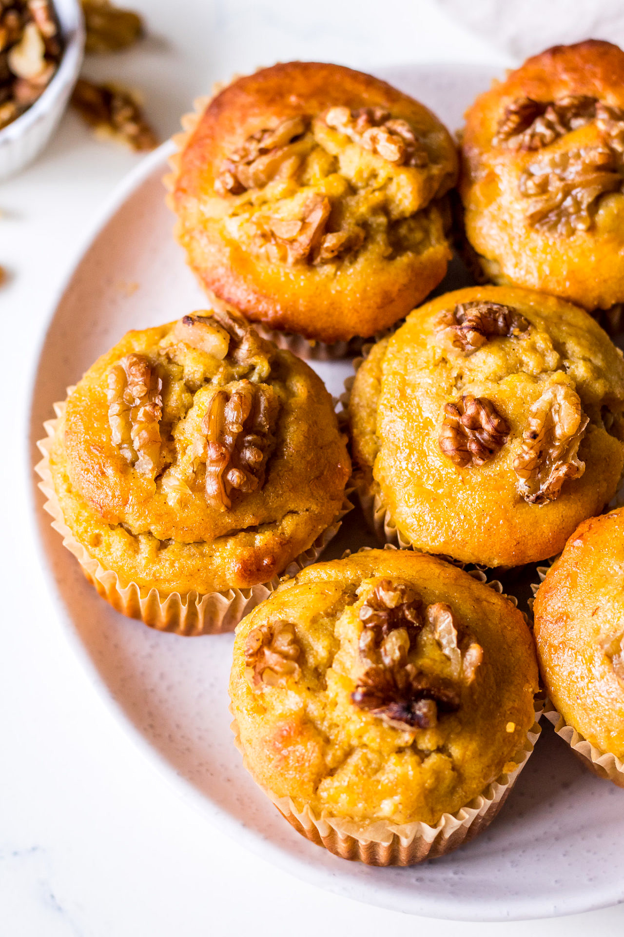 Close up plate of pumpkin, banana and walnut muffins, white ceramic plate on a linen napkin