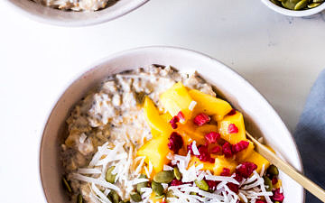 Two ceramic bowls with overnight oats, mango, coconut and raspberries