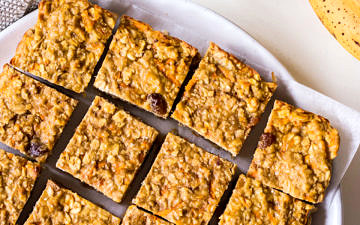 Banana oatmeal bars on a white plate with rolled oats and bananas