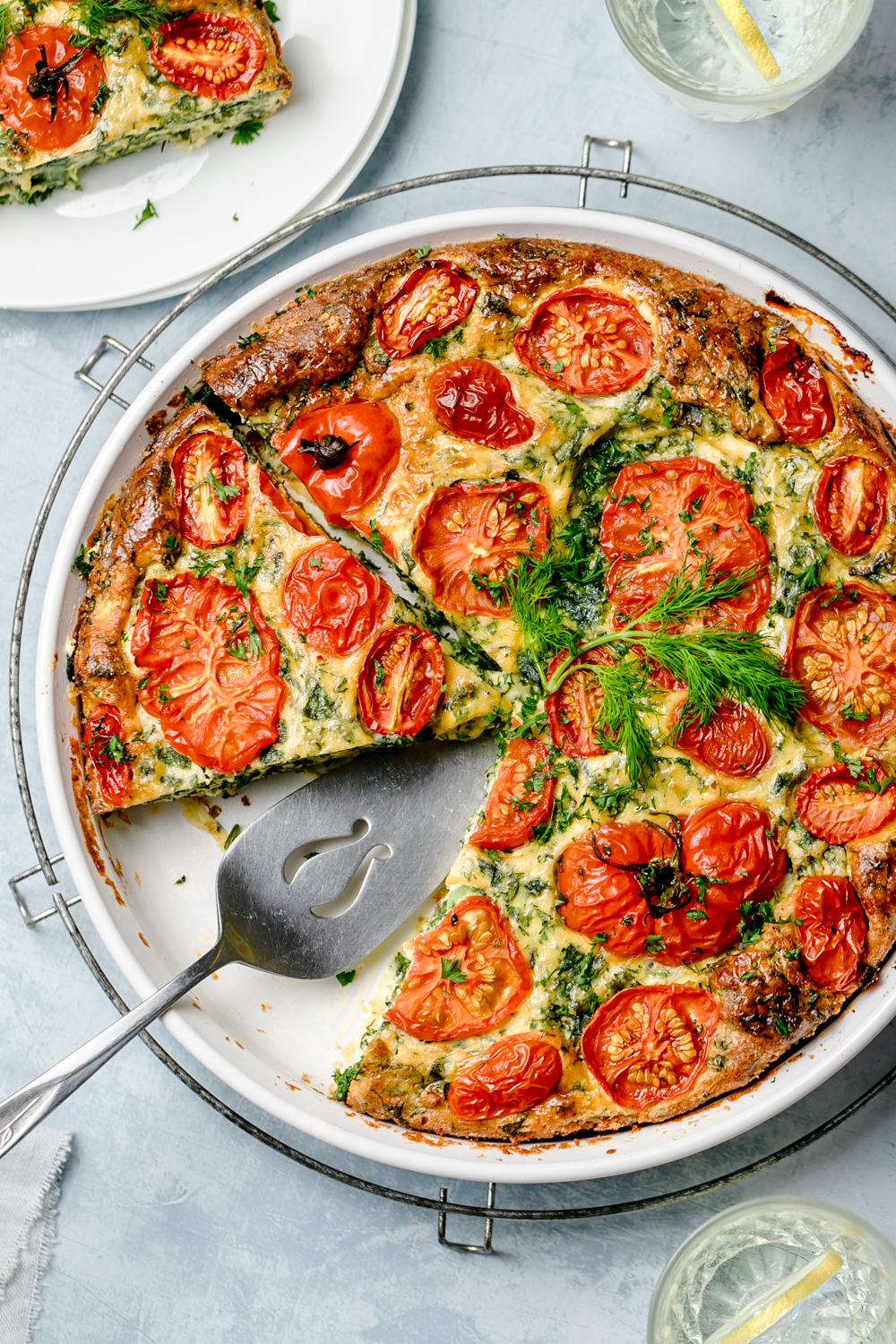Crustless ricotta kale pie in white baking dish sitting on top of a round cooling rack