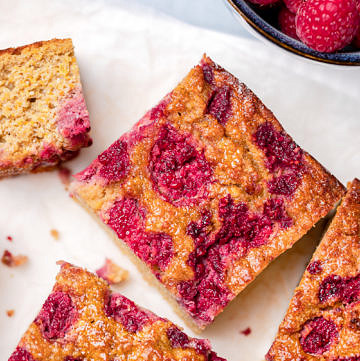 Orange cake topped with raspberries cut into square slices