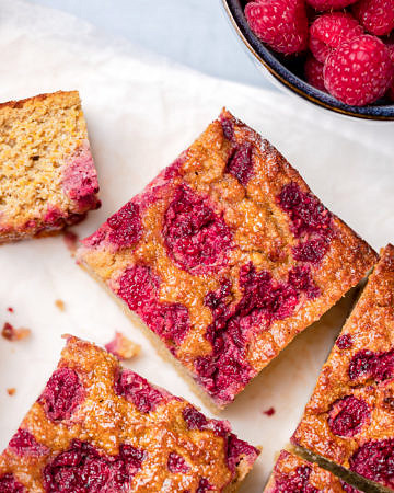 Orange cake topped with raspberries cut into square slices