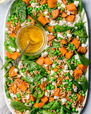 Salad of baby spinach, sweet potato and peas topped with feta, seeds and mustard dressing