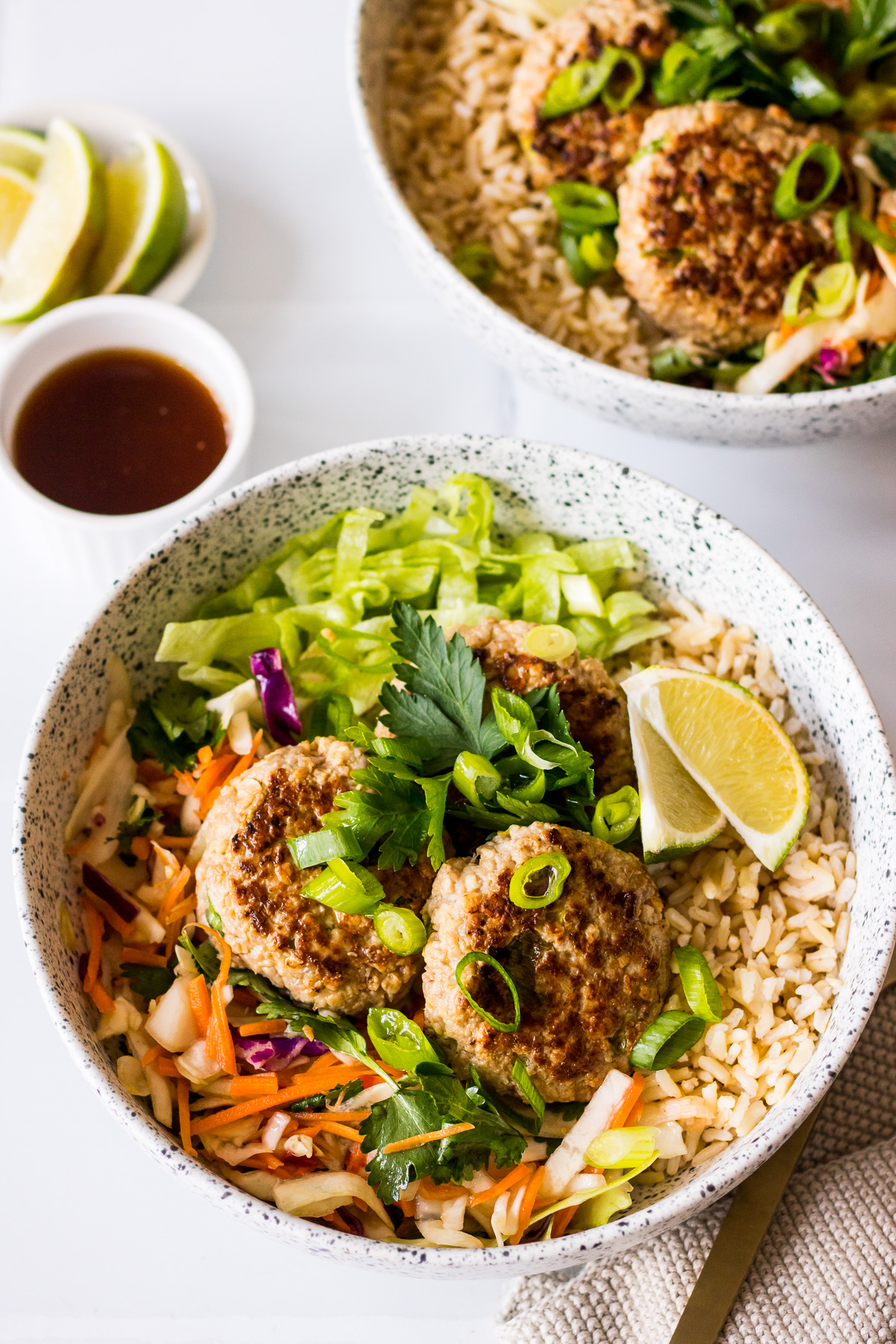 Lemongrass and ginger pork patties in a ceramic bowl with brown rice and salad