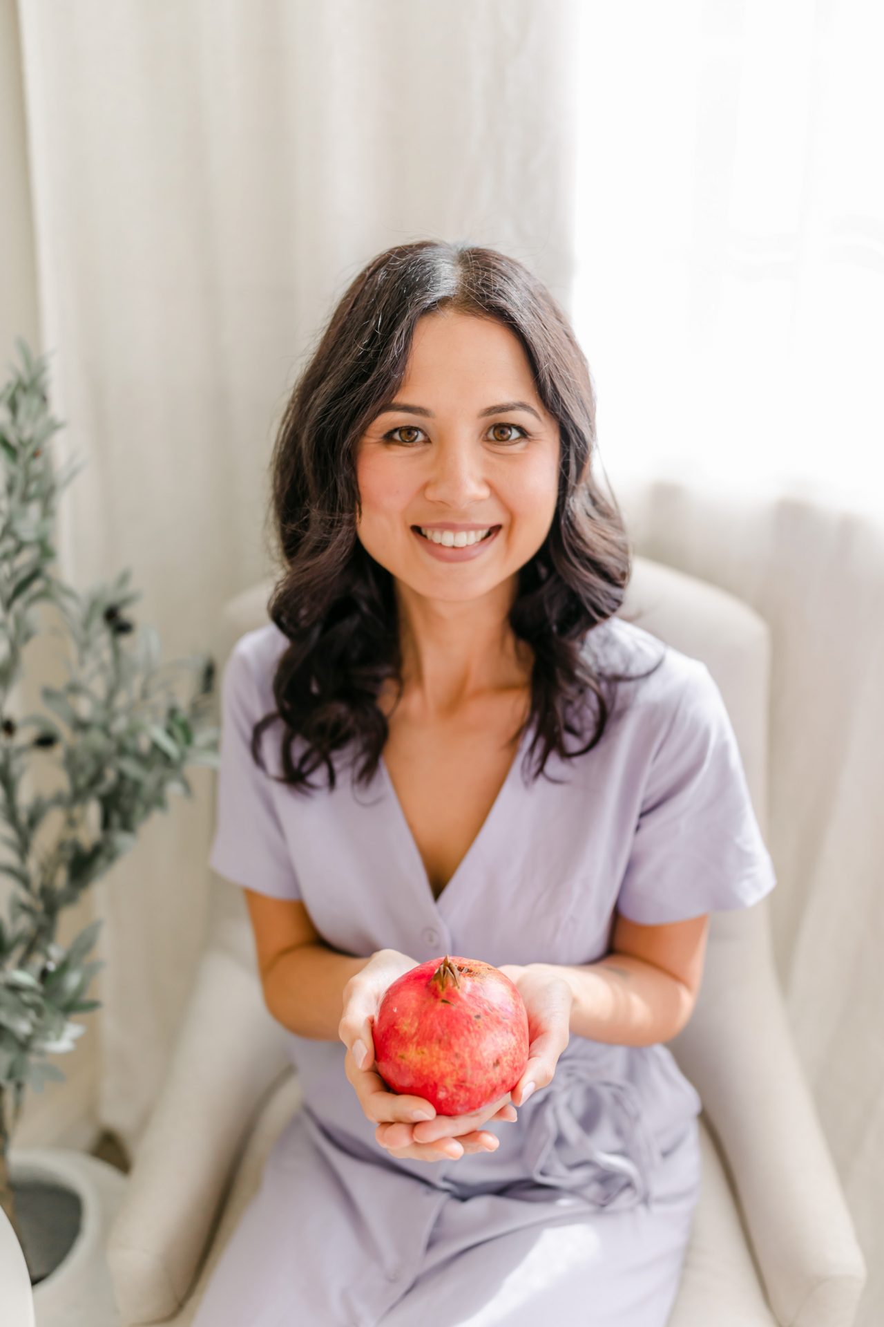 Monique Cormack wearing a purple dress holding a pomegranate