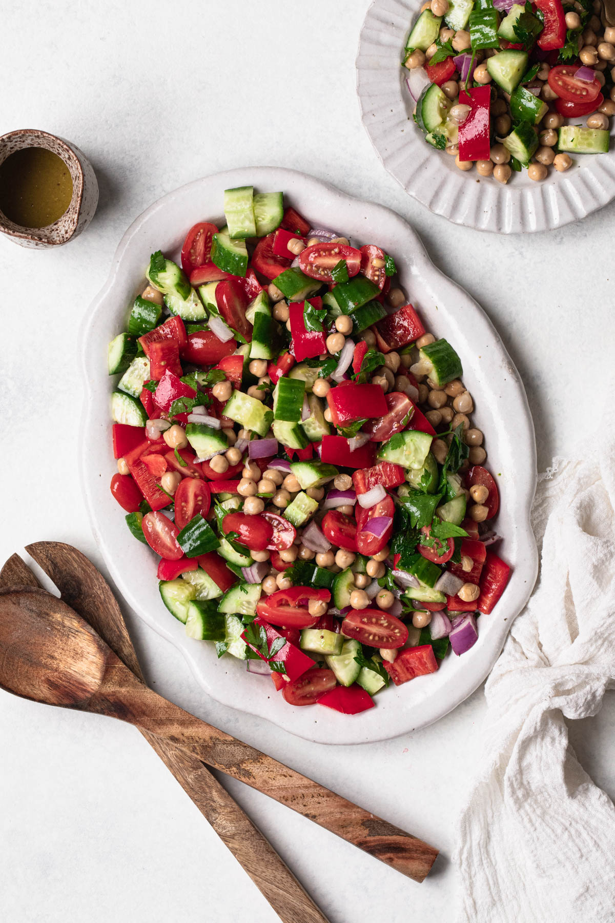 White oval platter with a chop salad of cucumber, tomato, capsicum, onion, chickpeas and parsley