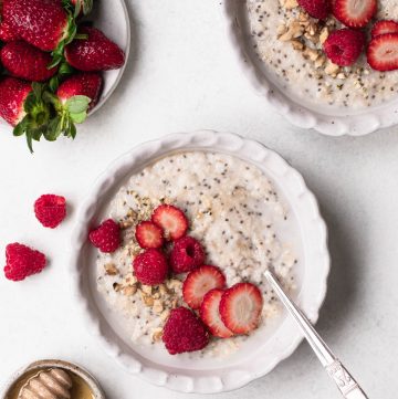 Bowl of oat and chia seed porridge topped with sliced strawberries
