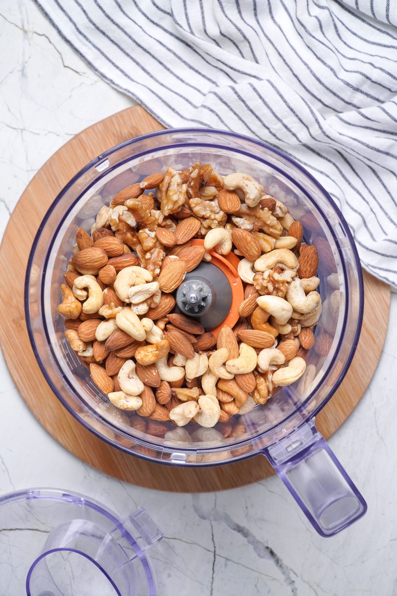 Mixed nuts in a food processor, top down view.