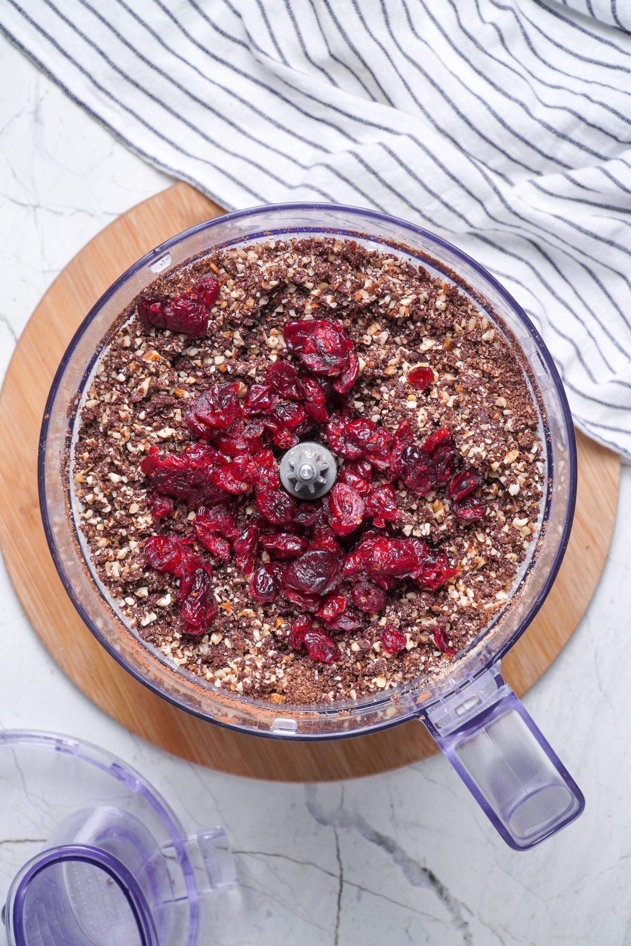 Making healthy chocolate truffles in a food processor. Mixed nuts, coconut flour, medjool dates, honey and cacao powder. Cranberries on top.