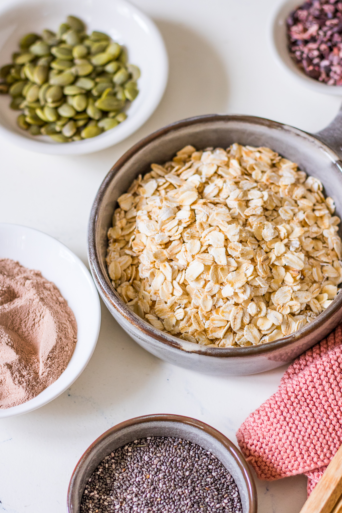 Small ceramic dishes with rolled oats, chia seeds, chocolate protein powder and pumpkin seeds