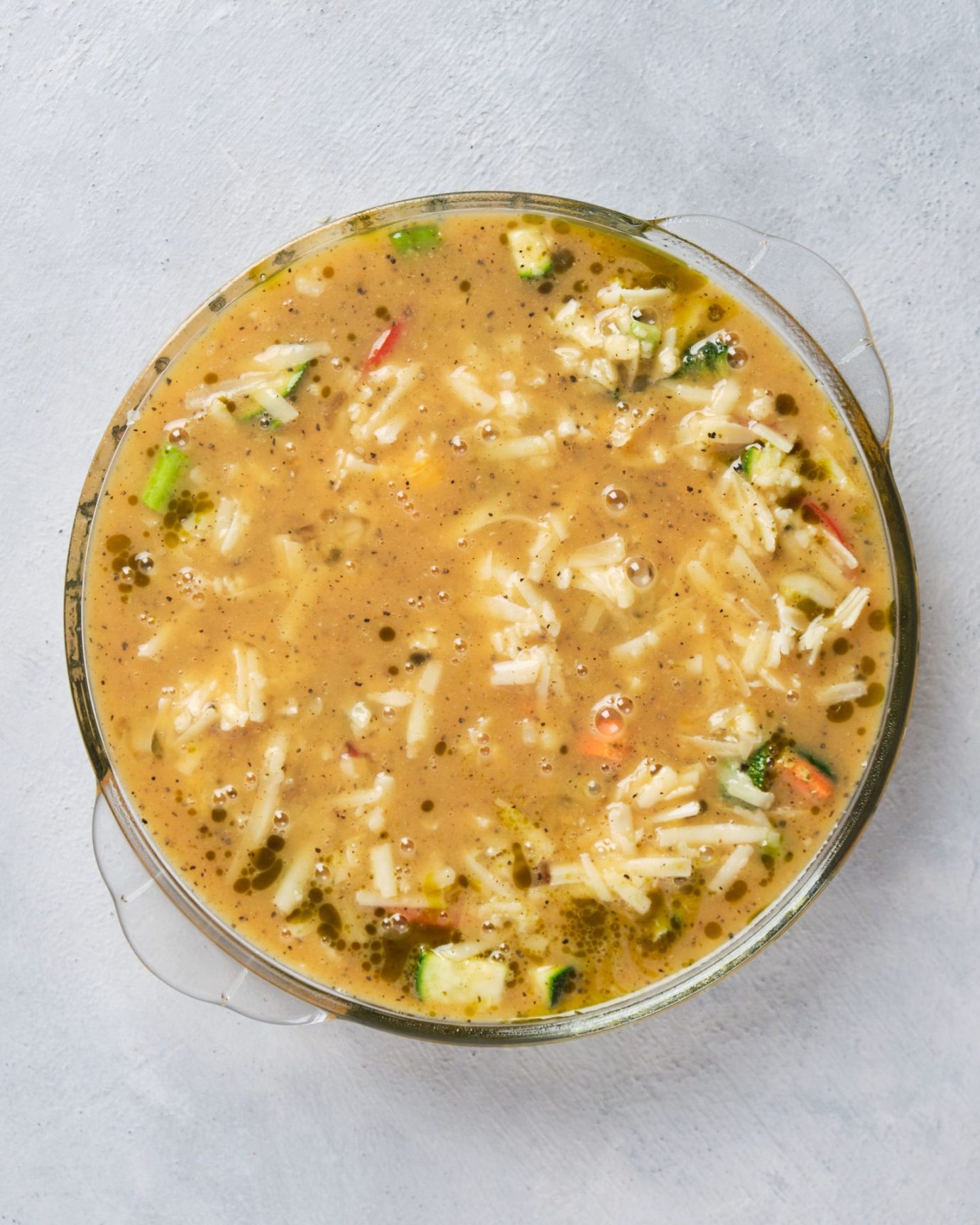 vegetables, shredded cheese and whisked eggs arranged in a baking dish, to prepare frittata