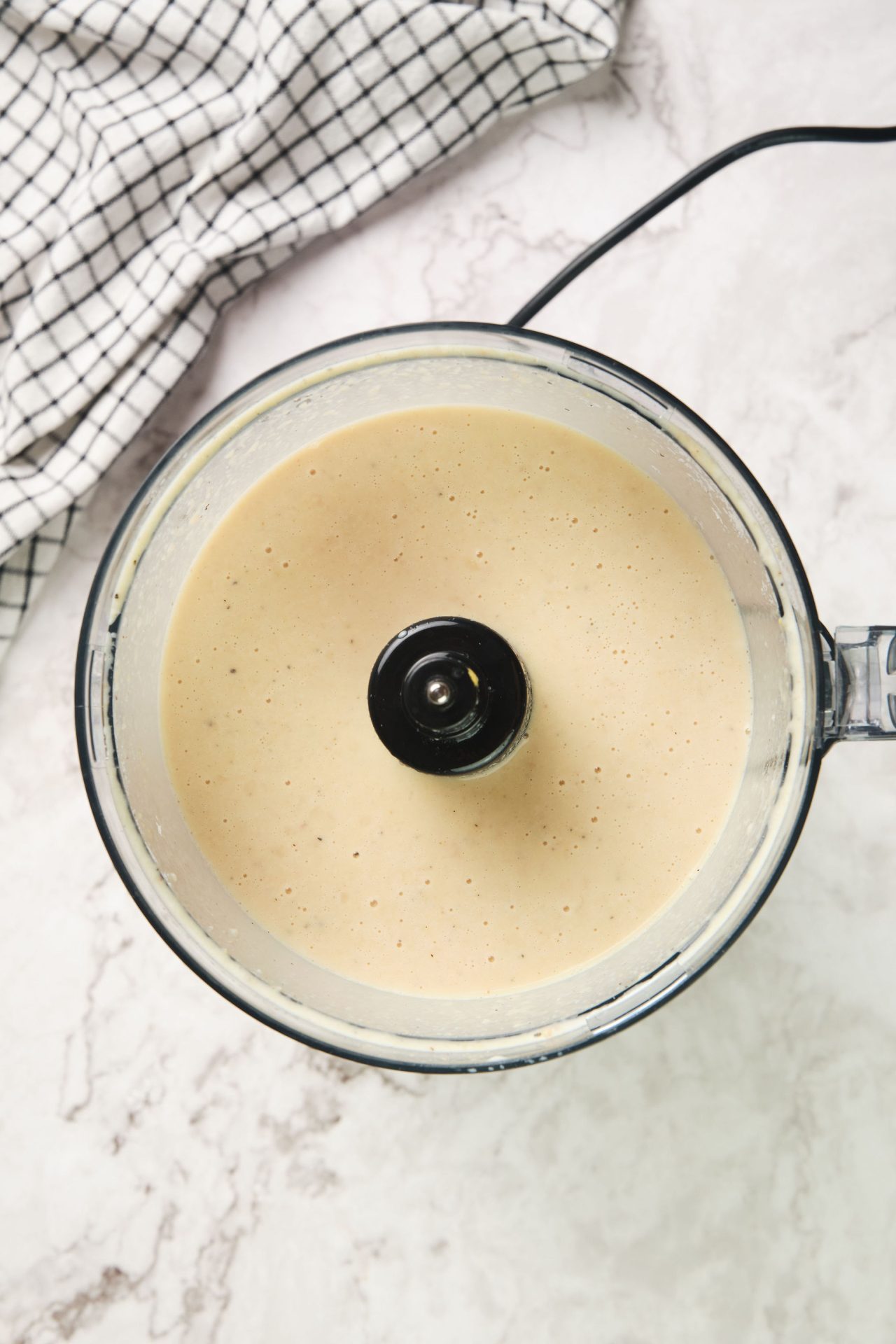 Food processor with white sauce inside, for tuna pasta bake