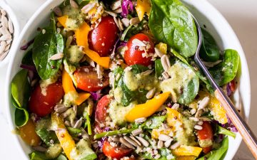 Image of a tuna salad with baby spinach, capsicum, cabbage and cherry tomatoes in a speckled white bowl