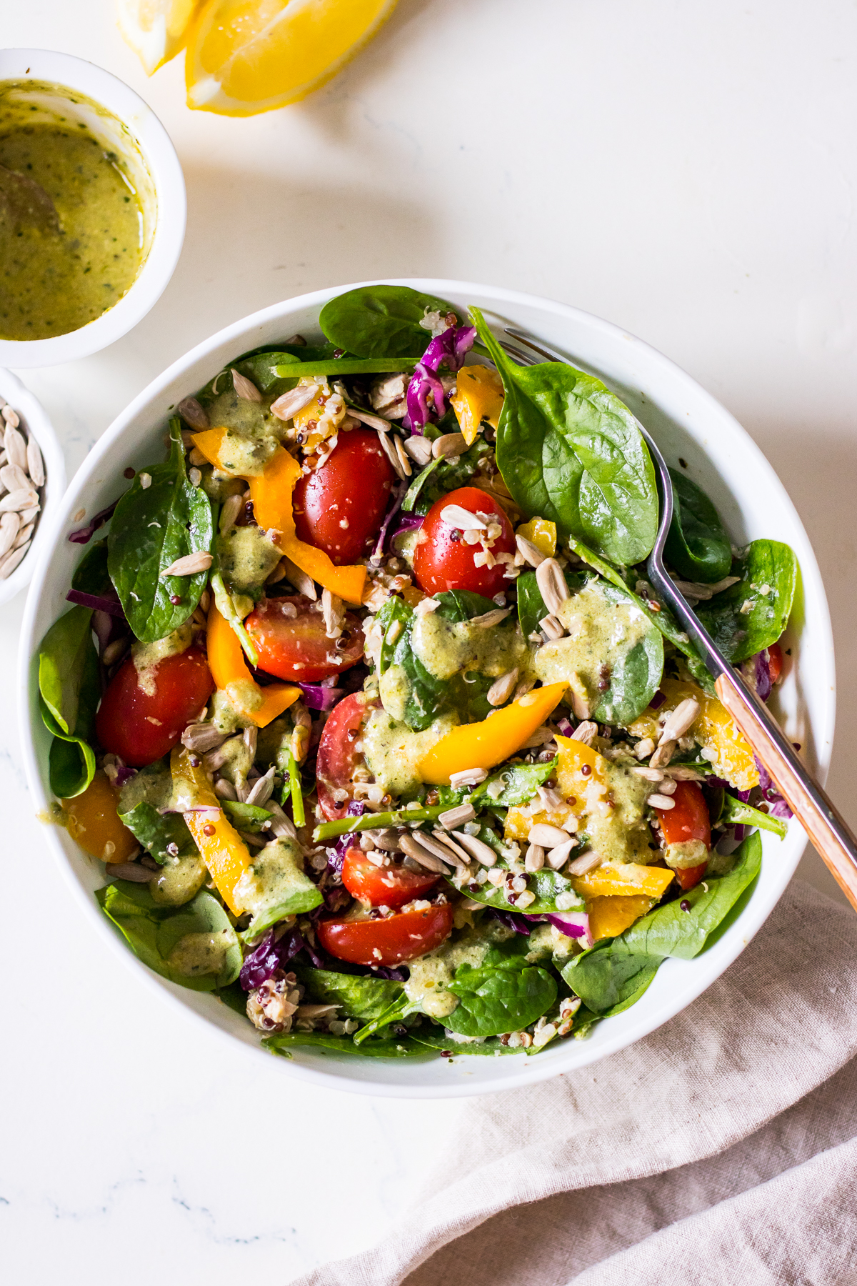 Image of a tuna salad with baby spinach, capsicum, cabbage and cherry tomatoes in a speckled white bowl