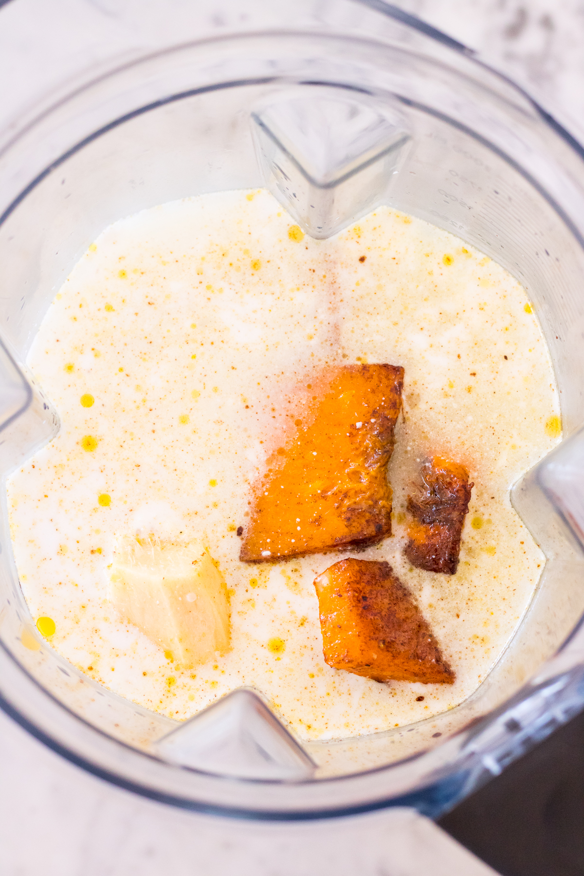 Image of pumpkin, coconut milk and ginger in a blender jug.