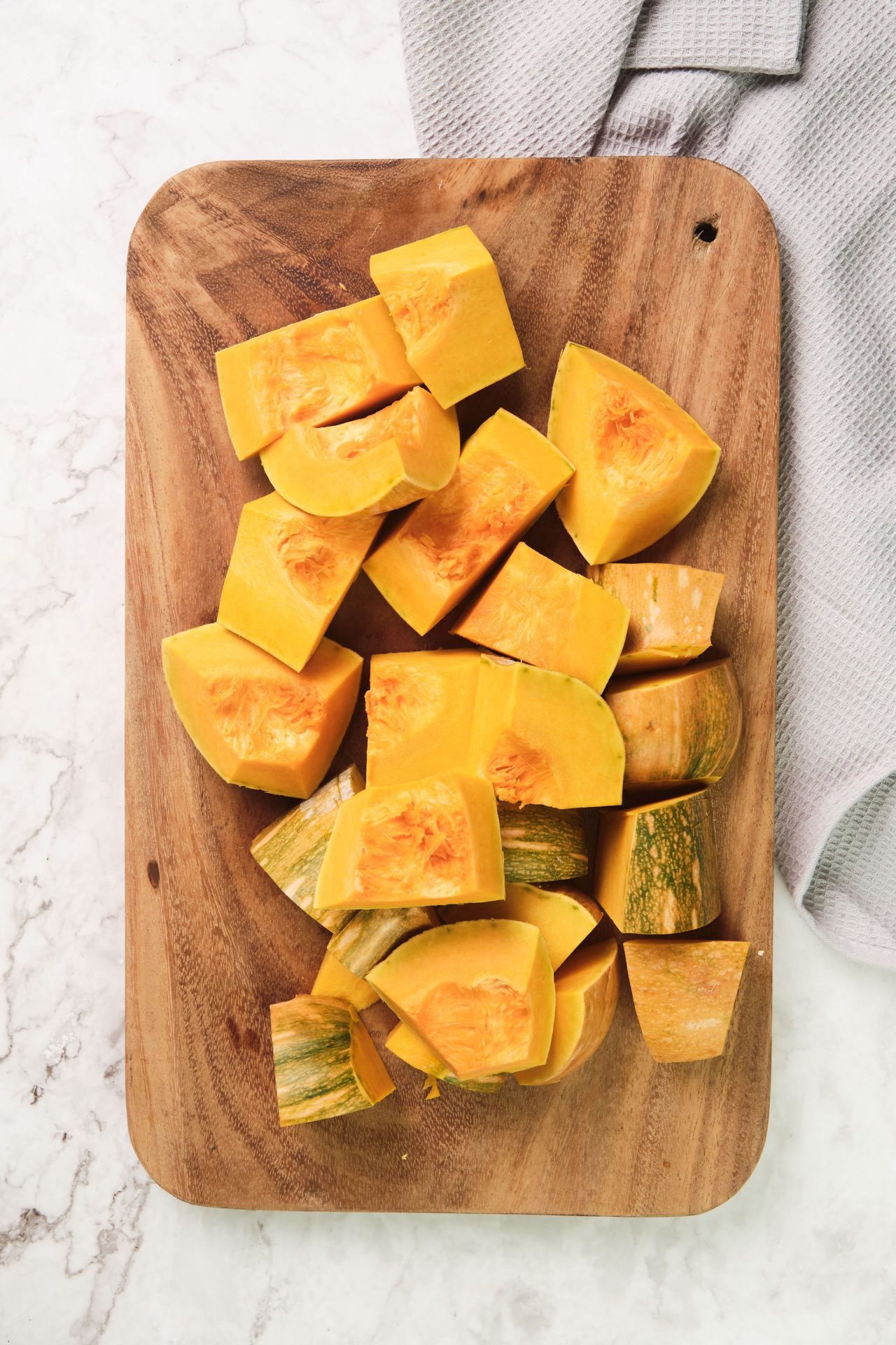 Chopped pumpkin pieces on a wooden chopping board