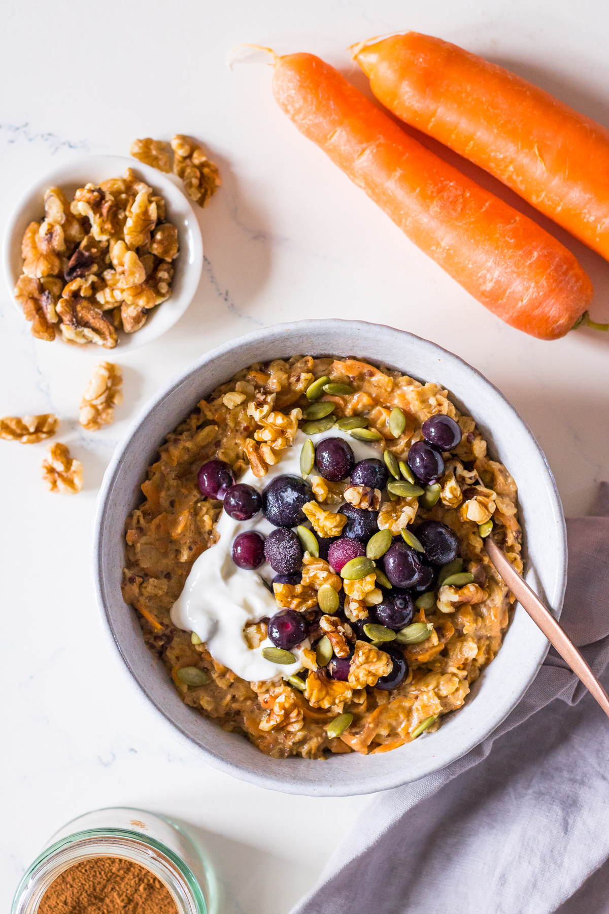 Carrot cake oatmeal topped with Greek yoghurt, blueberries and walnuts in a small bowl