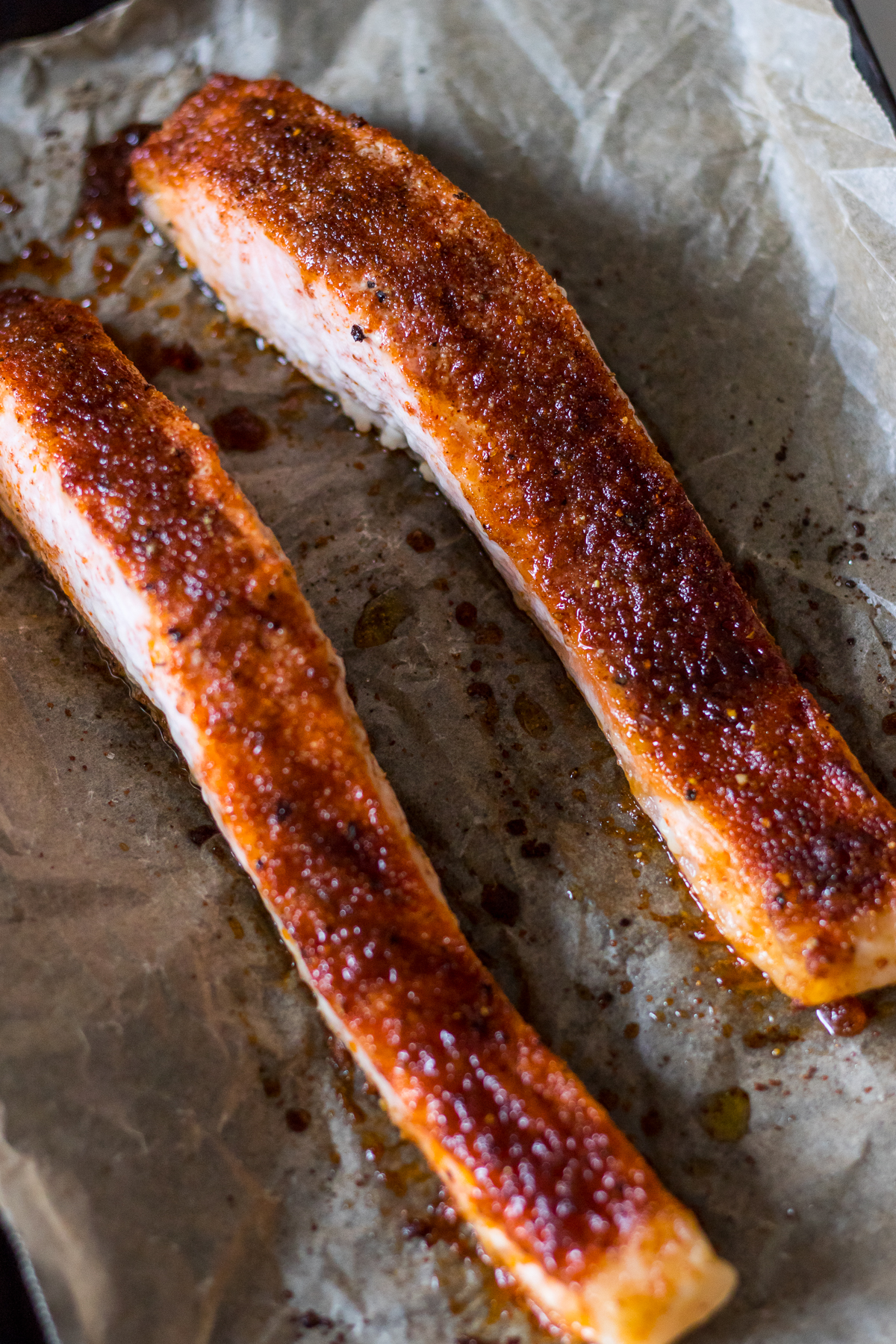Image of two pieces of salmon fillet on a baking tray baked with brown sugar