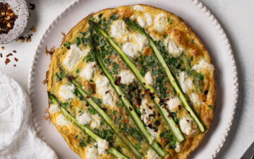 Pea and asparagus omelette on a white plate with silver cutlery, overhead shot