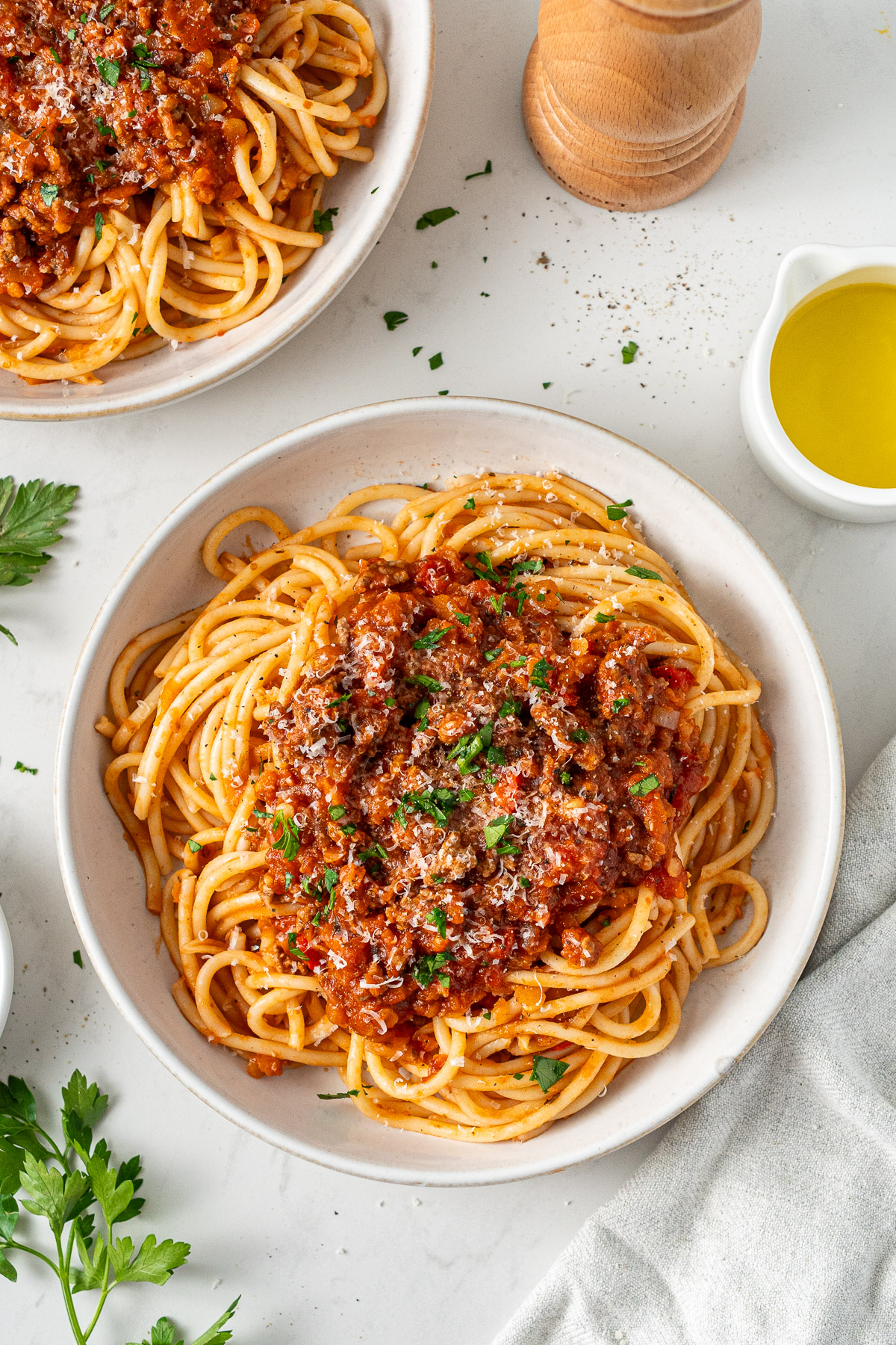A bowl of beef bolognese with red lentils served over spaghetti, topped with freshly grated parmesan.