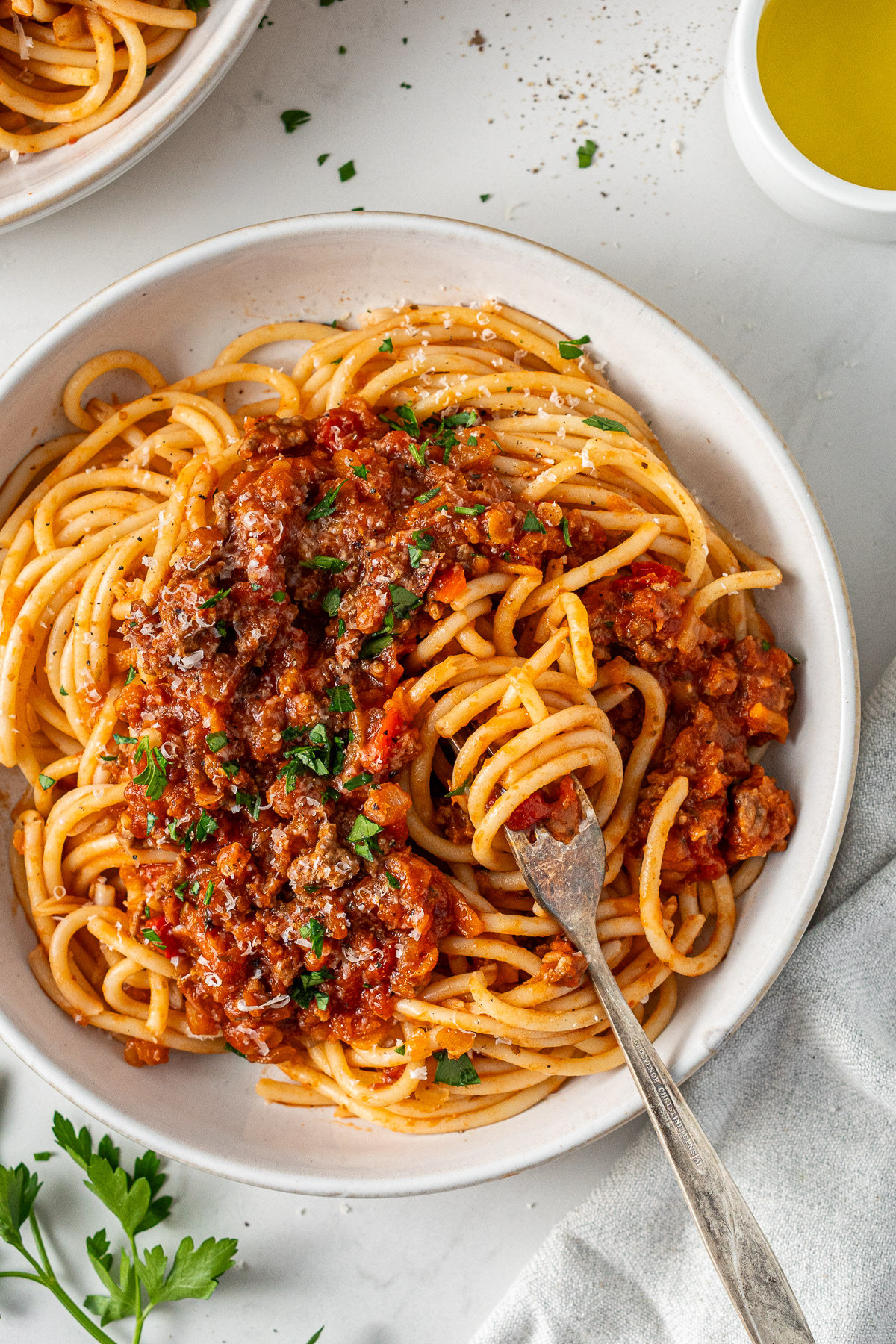 A bowl of beef bolognese with red lentils served over spaghetti, topped with freshly grated parmesan.